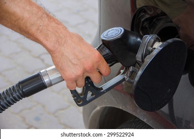 Closeup of man pumping gasoline fuel in car at gas station. Pumping gas at gas pump.
