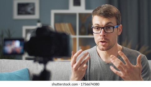 Close-up of man recording video blog using digital camera sitting on couch at home, front view - Powered by Shutterstock