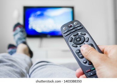 closeup of man relaxed in sofa using changing channel with remote