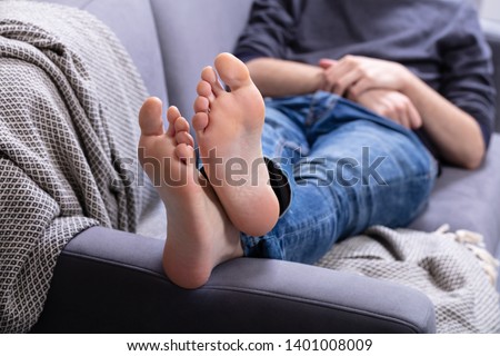 Close-up Of Man Relaxing On Sofa With His Legs Crossed In Home