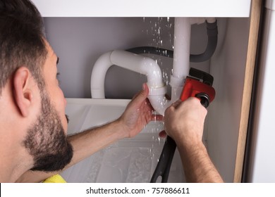 Close-up Of A Man Repairing Sink Pipe Leakage With Adjustable Wrench