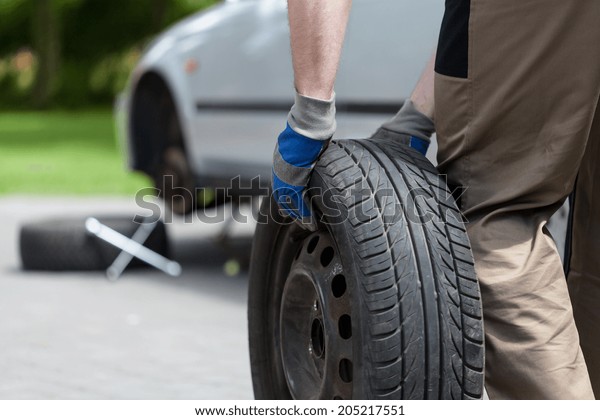 Close-up of a man rolling\
a spare wheel
