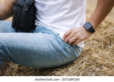 Close-up of man sits on hay bench and take phone from his pocket