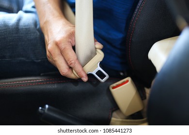 Close-up of a man sitting in his car and fastening seat belt
