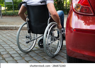 Close-up Of A Man Sitting On A Wheelchair Near His Car