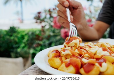 Closeup Of A Man, Sitting At An Outdoors Restaurant Table, Eating Some Typical Spanish Patatas Bravas, Fried Potatoes With A Hot Sauce