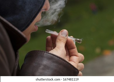 A Closeup Of A Man Smoking Weed In A Short Glass Pipe