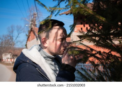 A Closeup Of A Man Sniffing A Tree Branch