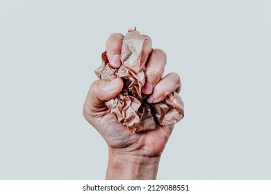 closeup of a man squeezing a ball of brown paper in his hand in front of an off-white background