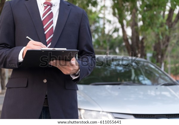 Close-up Of A Man Standing In Front Of Car Holding\
Clipboard In His Hand.
