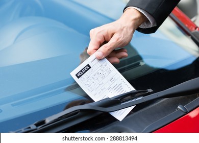 Close-up Of A Man Taking Parking Ticket On Car's Windshield