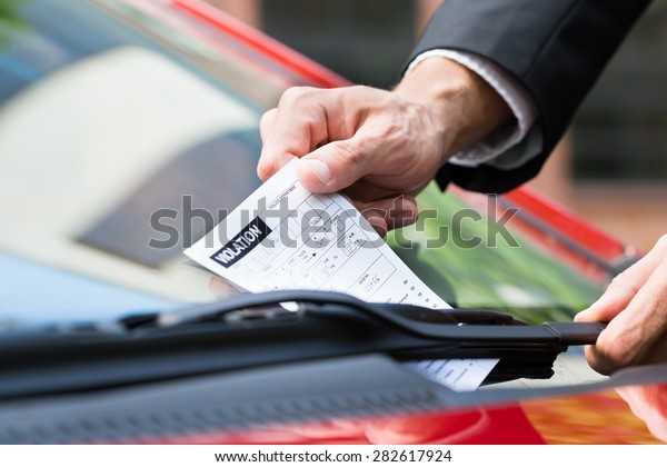 Close-up Of A Man Taking Parking Ticket On\
Car\'s Windshield