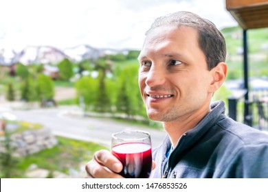 Closeup Of Man Tasting Red Wine By View Of Crested Butte Snow Mountains From Apartment Balcony Window