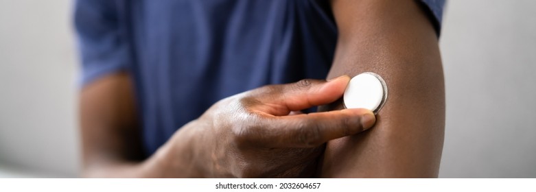 Close-up Of A Man Testing Glucose Level With A Continuous Glucose Monitor On His Arm