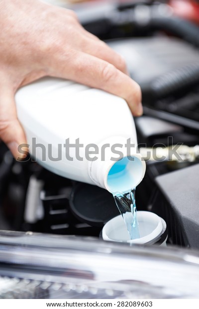 Close-Up
Of Man Topping Up Windshield Washer Fluid In
Car