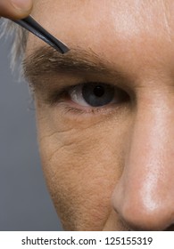 Closeup Of Man With Tweezers Plucking Eyebrows