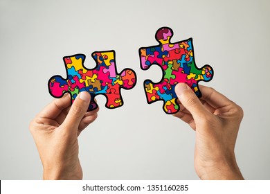 closeup of a man with two puzzle pieces patterned with many puzzle pieces of different colors, symbol of the autism awareness, on a white background - Powered by Shutterstock