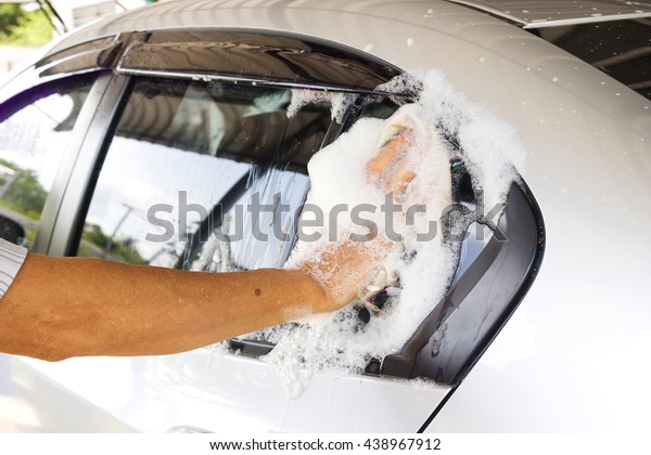 Closeup man\
use cloth washing a silver car at\
home.