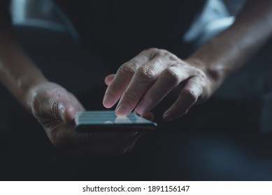 Close-up Of Man Using Mobile Phone Surfing Internet. Person Holding Smartphone With Light On Screen And Chatting Via Social Media Apps At Night With Dark Background. Internet Technology, Front View