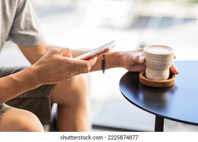 Close-up of a man using a smartphone in a coffee shop.