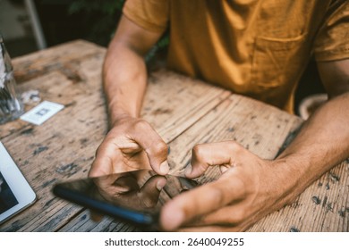 Closeup of man using smartphone while sitting at table in coffee shop