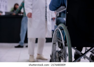 Closeup Of Man Using Wheelchair In Front Of Medical Doctor In Private Hospital Reception For Routine Checkup. Selective Focus On Senior Man Living With Disability At Clinic Reception For Appointment.