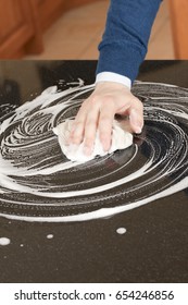 Closeup Of A Man Washing Or Cleaning A Black Granite Countertop 