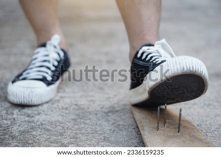 Closeup man wear shoes is stepping on rusty metal nail on wood. Concept, unsafe , risk for dangerous tetanus. Be careful and look around during walking  on the floor or risk places. Accident        