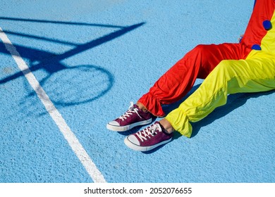 Closeup Of A Man, Wearing A Colorful Clown Costume, Sitting An Outdoor Basketball Court