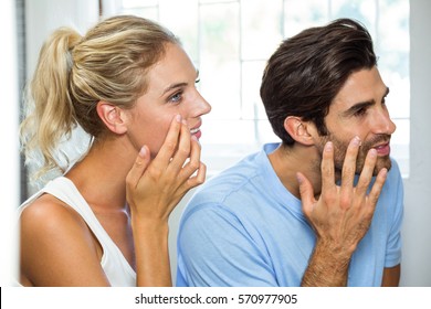 Close-up Of Man And Woman In Bathroom Applying Moisturizer On Their Face