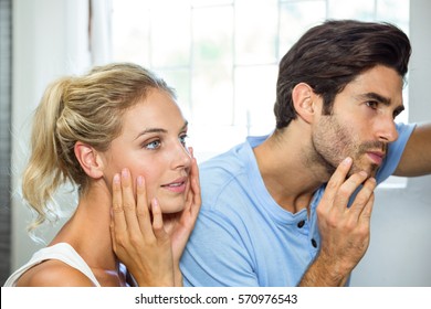 Close-up Of Man And Woman Checking Their Skin In Bathroom