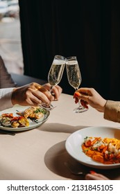 Closeup of a man and woman clinking glasses with champagne at a restaurant. - Shutterstock ID 2131845105