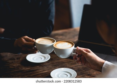 Close-up of a man and woman clinking a white coffee cup in a coffee shop. while talking at work - Powered by Shutterstock