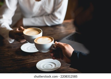Close-up of a man and woman clinking a white coffee cup in a coffee shop. while talking at work - Shutterstock ID 2208312585