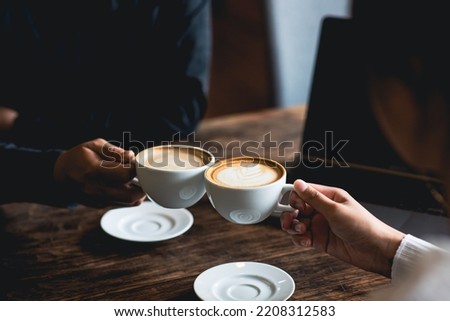 Close-up of a man and woman clinking a white coffee cup in a coffee shop. while talking at work
