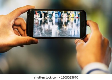 Closeup Of Man Or Woman Taking A Picture Of The Legs Of A Big Group Of People Waiting To Enter At Their Flight At The Airport - Waiting To Enter At Their Gate Or Ckeck-in