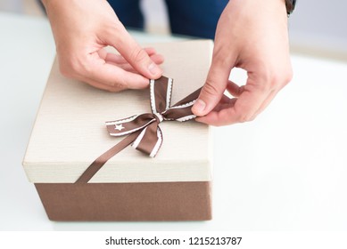 Closeup Of Man Wrapping Gift. Person Tying Bow On Gift Box. Gift Concept. Cropped View.