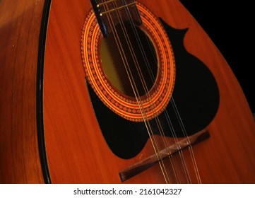 A  closeup of a mandolin string instrument. This instrument is used in both traditional Italian and Greek music.