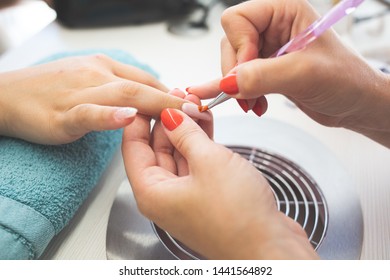 Closeup of Manicurist Applies Nail Gel Polish on Finger. Girl client holds hand on the client on Towel. Beautician gently manicured service