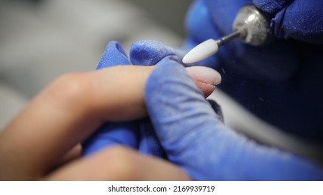 Close-up of manicurist doing hardware manicure to female client using special apparatus. Beauty day and body care concept Foto Stock