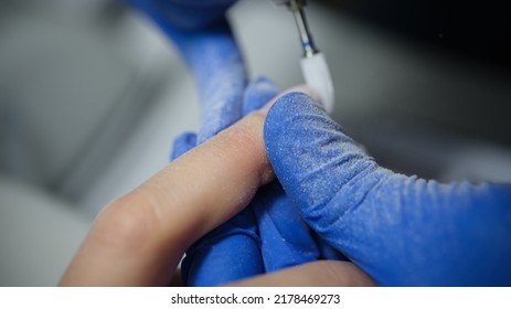 Close-up of manicurist in gloves doing hardware manicure to client using special apparatus. Beauty day and body care concept Foto Stock