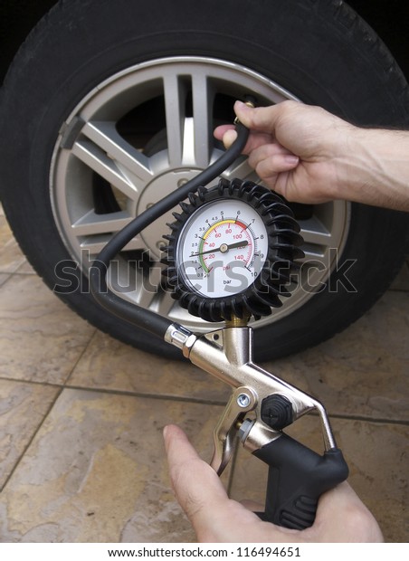 Close-up of manometer and man hands checking tire\
pressure with gauge.