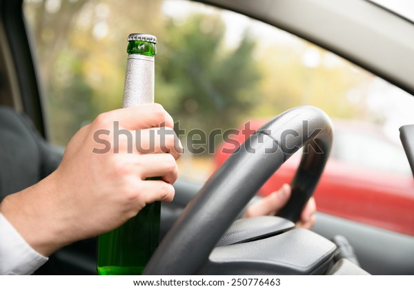 Close-up Of A Man's Hand In Car Holding Beer
Bottle While Driving