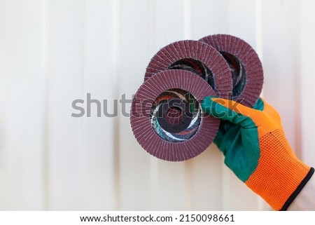 close-up of a man's hand in a construction glove holding abrasive tools. Banner with space for text