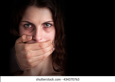 Closeup of a mans hand covering a womans mouth. Concept of domestic violence or kidnapping. Dark mood. - Shutterstock ID 434370763