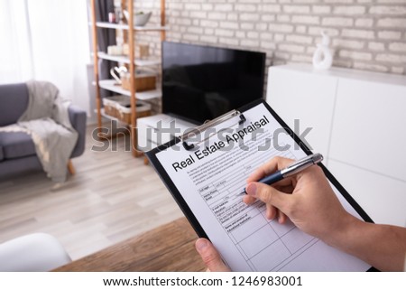 Close-up Of A Man's Hand Filling Real Estate Appraisal Form At Home