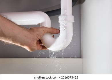 Close-up Of A Man's Hand Holding The Leakage White Sink Pipe In Kitchen