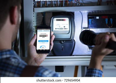 Close-up Of A Man's Hand Holding Mobile Phone Showing Electric Meter Reading And Holding Flashlight