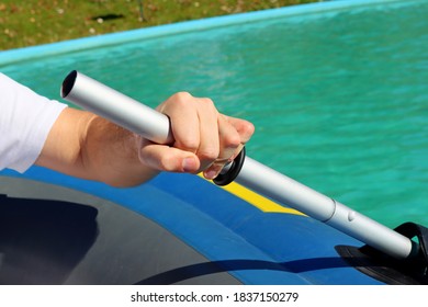 Close-up Of A Mans Hand Holding A Paddle From A Rubber Boat Against The Backdrop Of Blue Water.