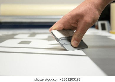 Close-up of a man's hand holding a trowel and preparing to make car stickers on vinyl